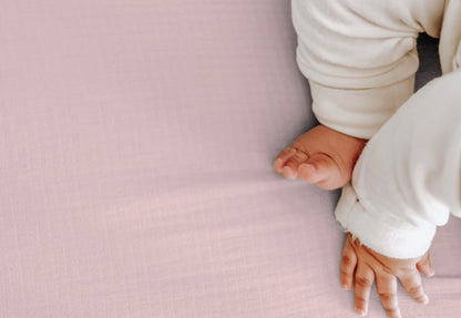 Close-up view of a baby's bare feet and hands on a soft pink textured blanket. 999-3020-PNP 999-3520-PNP