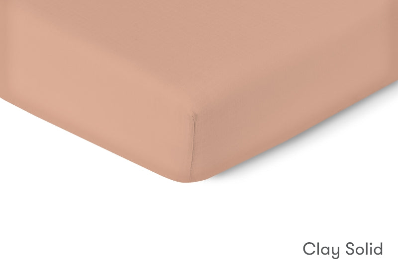 Close-up of a clay solid colored crib mattress sheet with a smooth finish, labelled "Clay Solid." 999-3020-CLY 999-3520-CLY