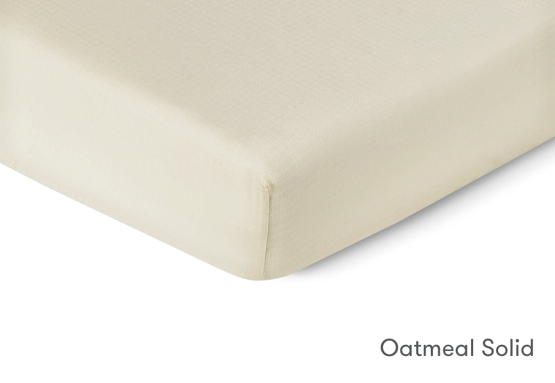 Close-up of a Newton Baby crib mattress sheet in 'Oatmeal Solid' color. 999-3020-ONO 999-3520-ONO