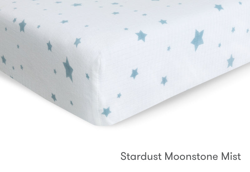Close-up of a crib mattress with a pale blue star pattern and the text "Stardust Moonstone Mist." 999-3020-SDW 999-3520-SDW