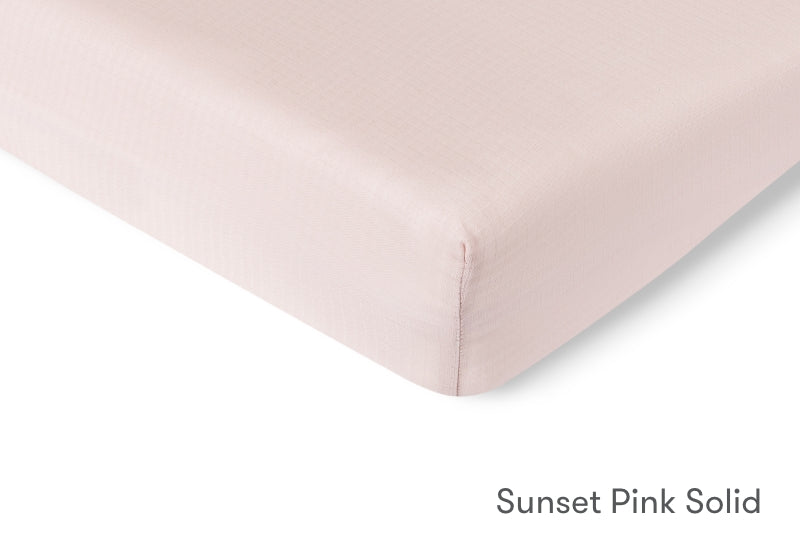 Close-up of a sunset pink solid crib mattress sheet by Newton Baby. 999-3020-PNP 999-3520-PNP