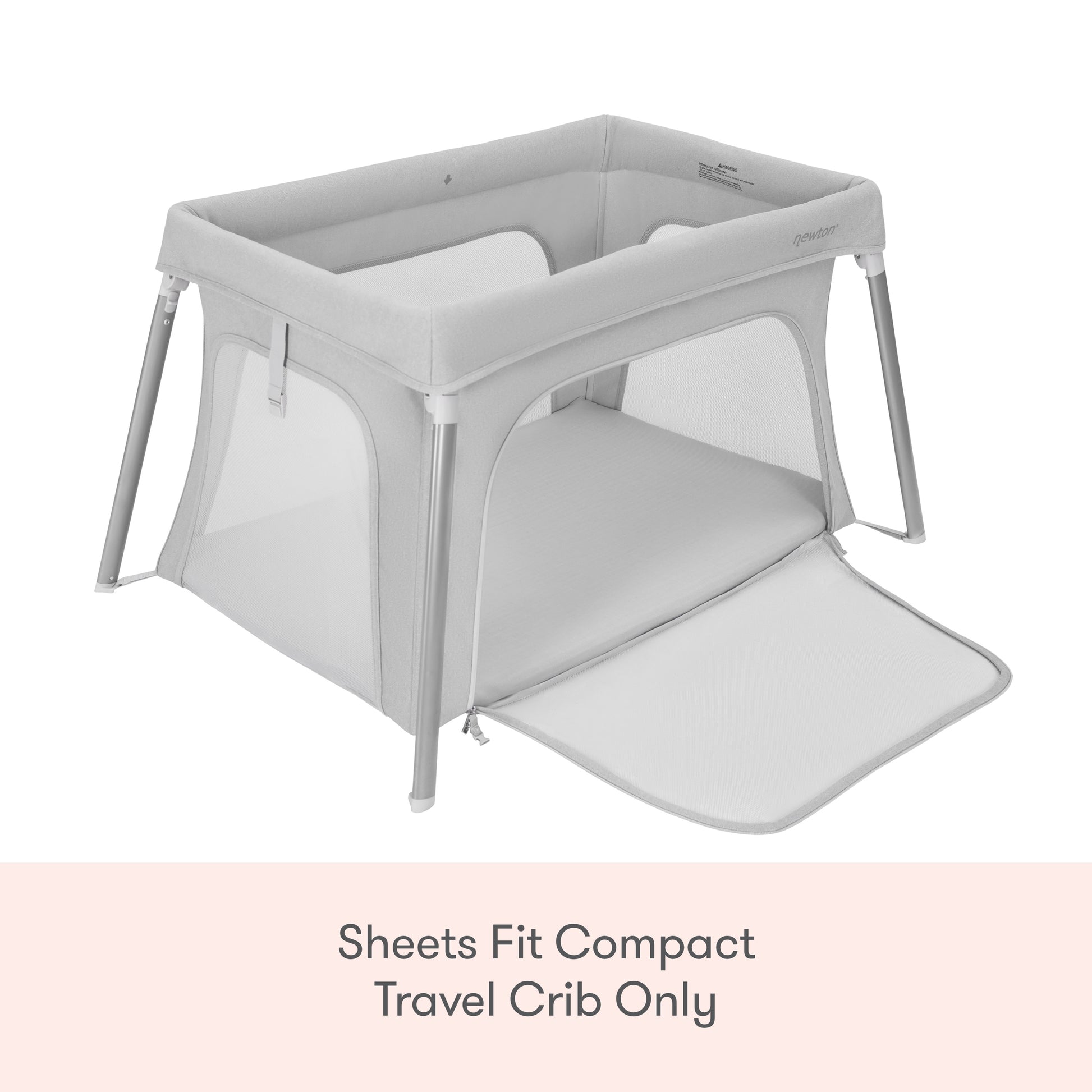 A Newton Baby Compact Travel Crib with light gray mesh sides and a zippered panel. Text below: Compact Travel Crib Sheets by Newton Baby fit this model only.
