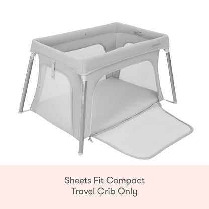 A Newton Baby Compact Travel Crib with light gray mesh sides and a zippered panel. Text below: Compact Travel Crib Sheets by Newton Baby fit this model only.