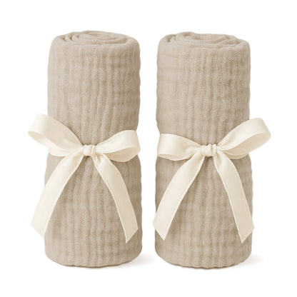 Two rolled-up Sandstone sheets for Compact Travel Crib with white ribbons on a white background. 999-5003-SAN