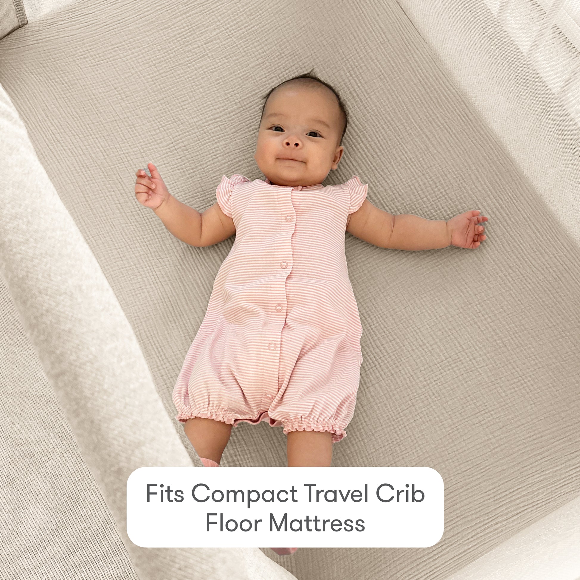 A baby in a pink romper lies on a light gray mattress in a crib. Text reads, "Newton Baby Compact Travel Crib Sheets: snug fit for added comfort on your travel crib mattress.