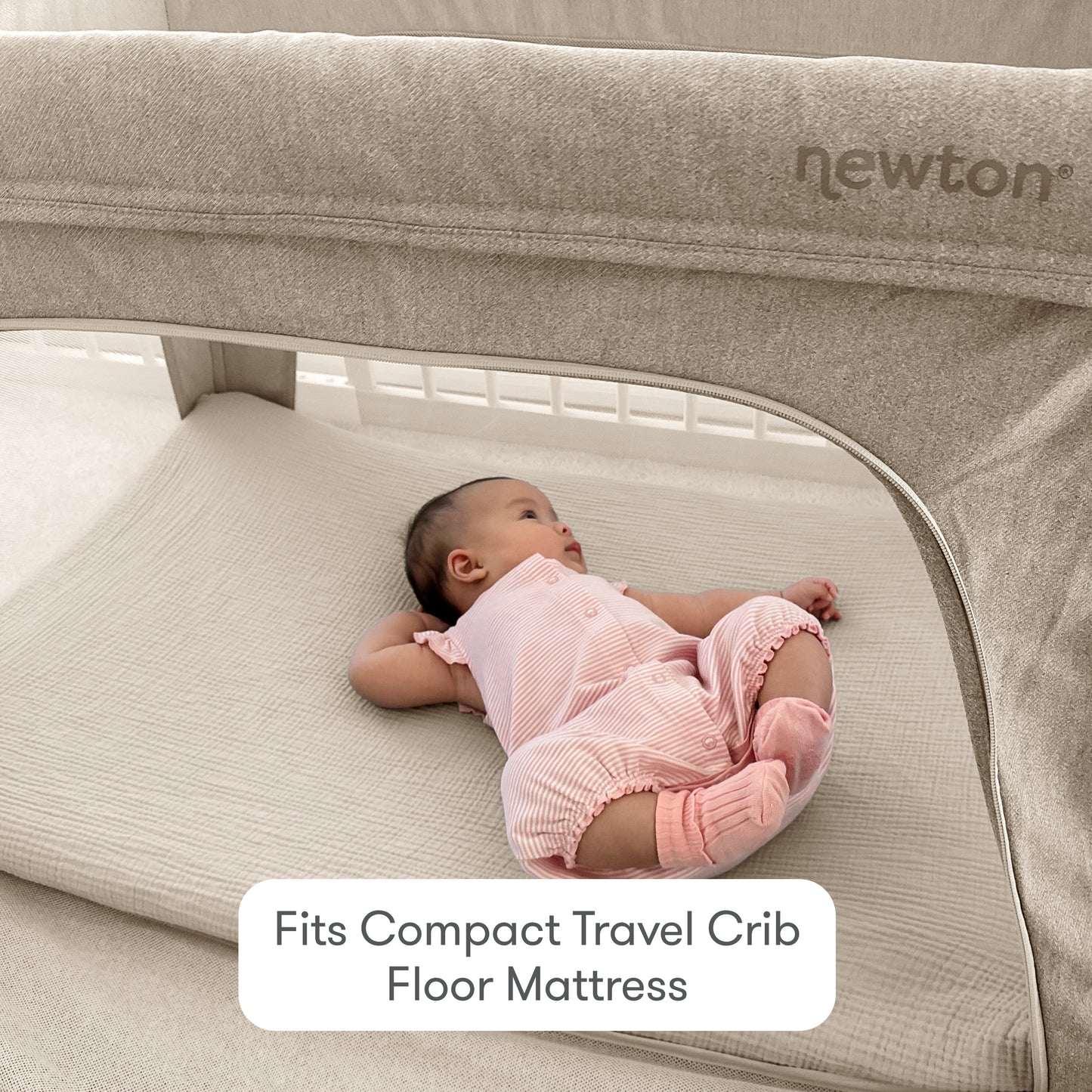 A baby in a pink outfit lies on a light mattress inside a travel crib. Text reads, Fits Compact Travel Crib Floor Mattress. Also shown is a soft cotton muslin Compact Travel Crib Sheet by Newton Baby, with the brand name visible on the crib.