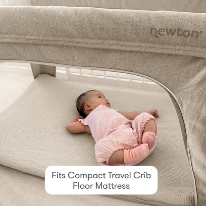 A baby in a pink outfit lies on a light mattress inside a travel crib. Text reads, Fits Compact Travel Crib Floor Mattress. Also shown is a soft cotton muslin Compact Travel Crib Sheet by Newton Baby, with the brand name visible on the crib.