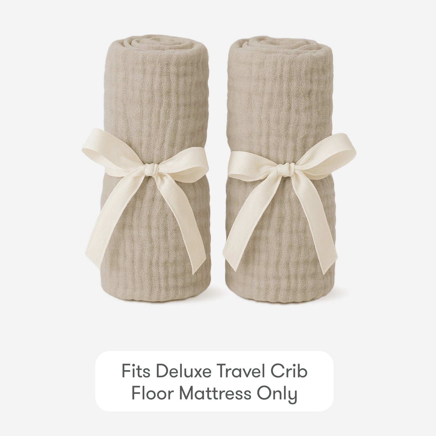 Two rolled beige Newton Baby Compact Travel Crib Sheets, tied with cream ribbons, are side by side on a white background. Text below reads: Fits Deluxe Travel Crib Floor Mattress Only.
