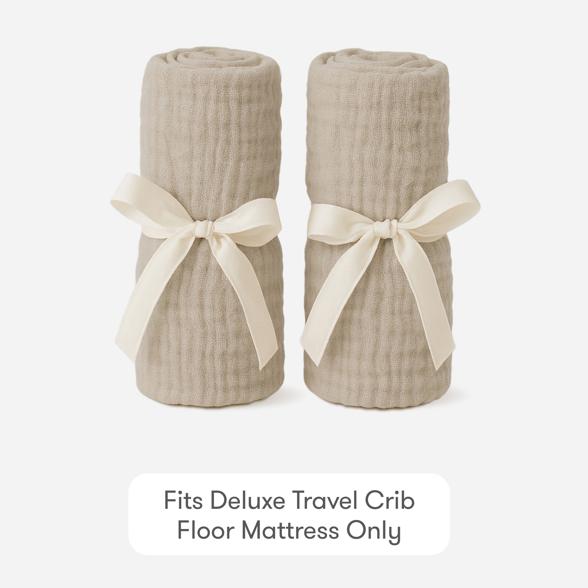 Two rolled beige Newton Baby Compact Travel Crib Sheets, tied with cream ribbons, are side by side on a white background. Text below reads: Fits Deluxe Travel Crib Floor Mattress Only.