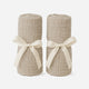 Two beige, rolled-up blankets stand upright, each tied with a cream ribbon, perfectly complementing your Newton Baby Compact Travel Crib Sheets—shown against a plain white background.