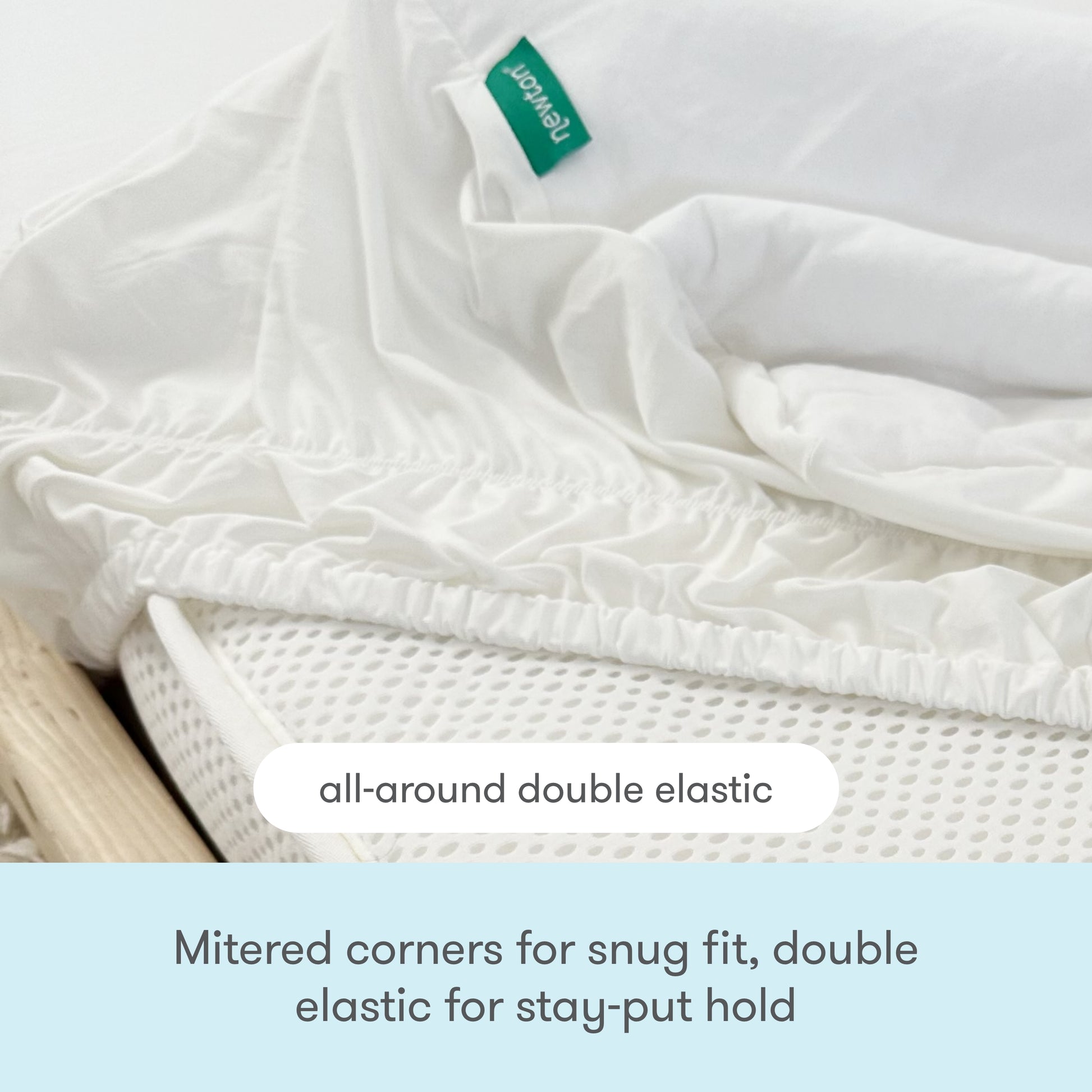 Close-up of Newton Baby’s Waterproof Organic Twin Mattress Pad on a mattress, showing mitered corners and all-around double elastic for a secure fit. Features a green tag and is perfect as a kids twin mattress pad.