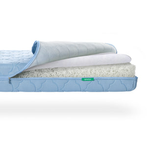 A Newton Baby Crib Mattress with the zippered cover partially peeled back to reveal a breathable, white, layered, webbed core. skip