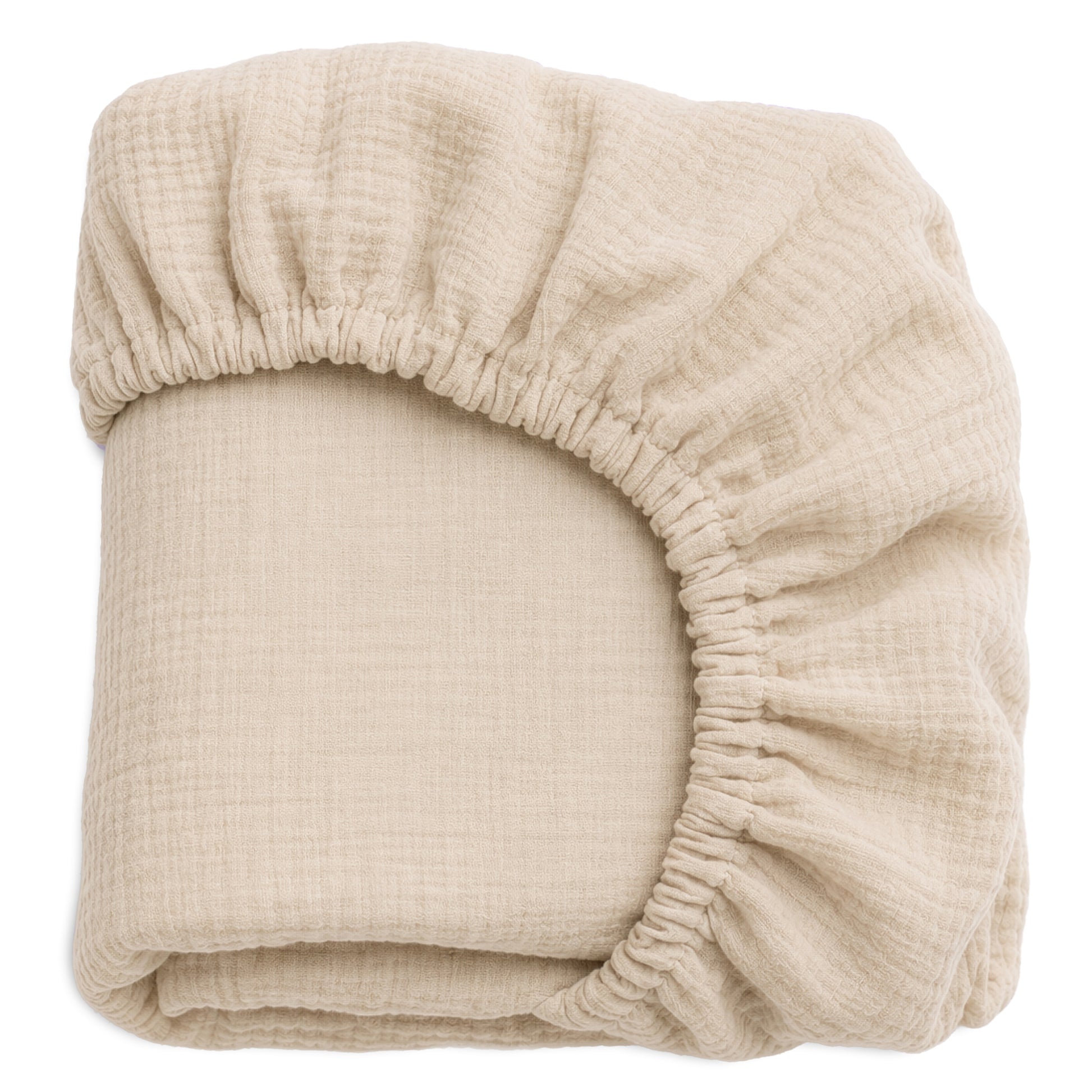 A beige, textured Newton Baby Nest Bassinet Extra Sheet—breathable and neatly folded—displays its elastic edge and gathered fabric at one corner.