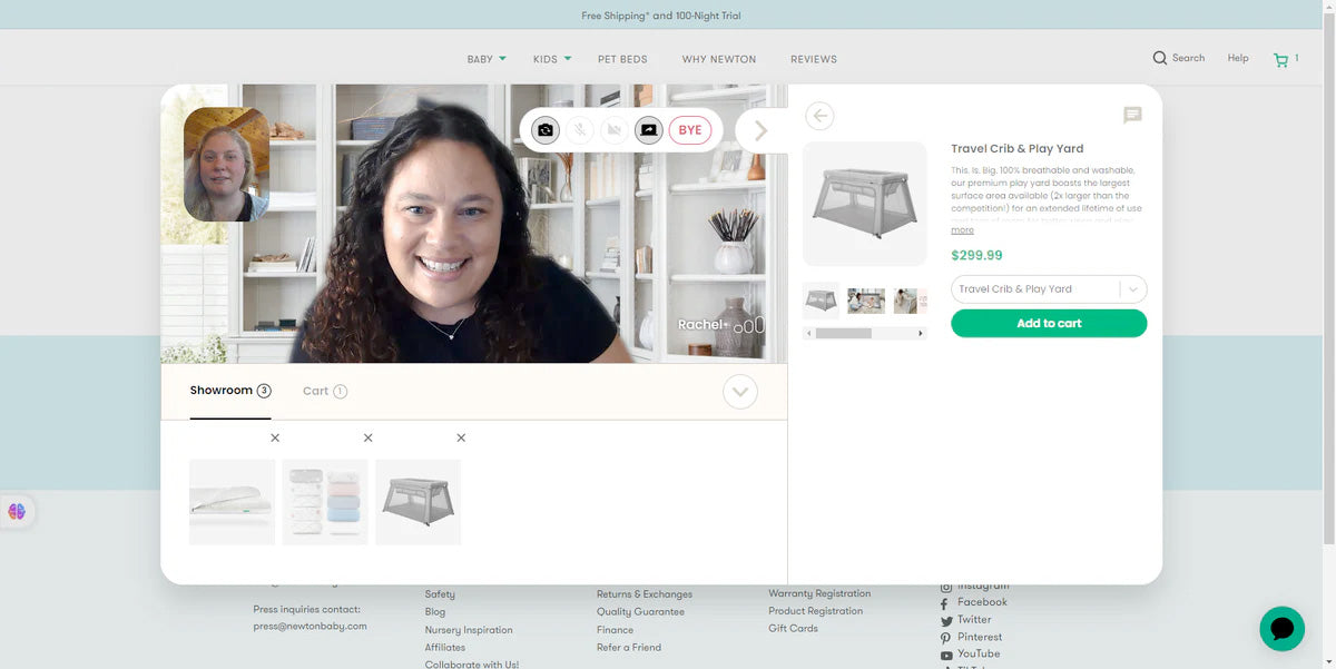 A woman with curly hair smiles during a video call with another woman. The screen also displays an online shopping page for a travel crib and play yard, with images and purchasing options.