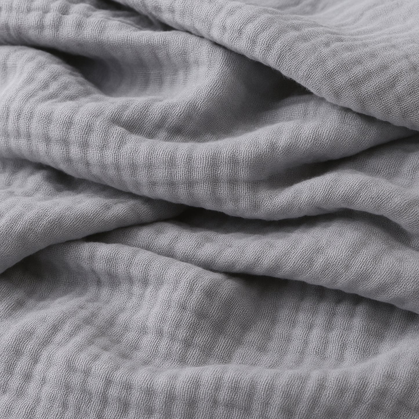 Close-up of Newton Baby Breathable, Organic Cotton Sheets (2-pack) in soft light gray, showing the crinkled muslin texture and gentle folds for a cozy, inviting look.