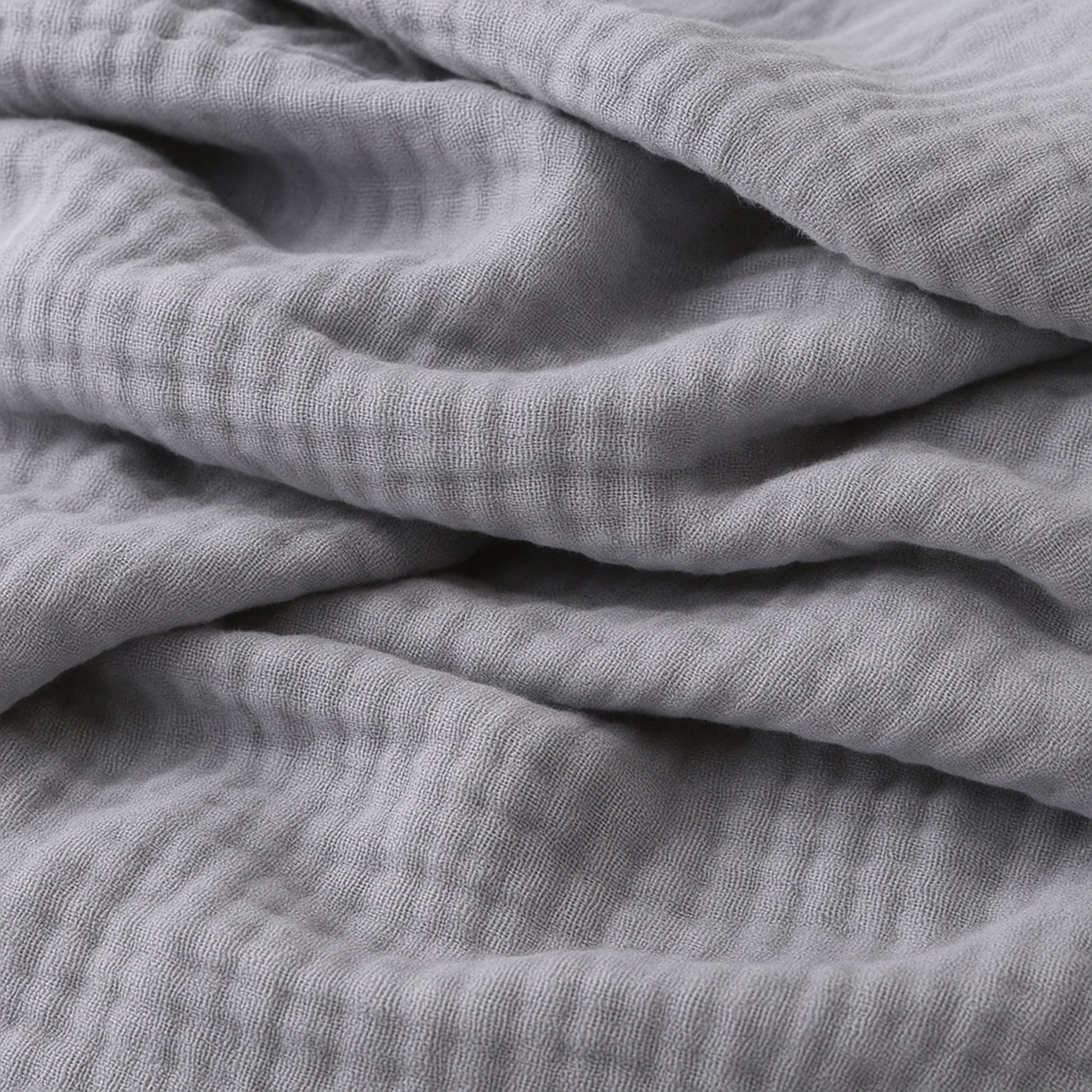 Close-up of Newton Baby Breathable, Organic Cotton Sheets (2-pack) in soft light gray, showing the crinkled muslin texture and gentle folds for a cozy, inviting look.