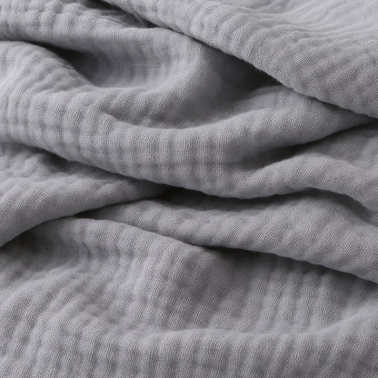 Close-up of Newton Baby Breathable, Organic Cotton Sheets (2-pack) in soft light gray, showing the crinkled muslin texture and gentle folds for a cozy, inviting look.