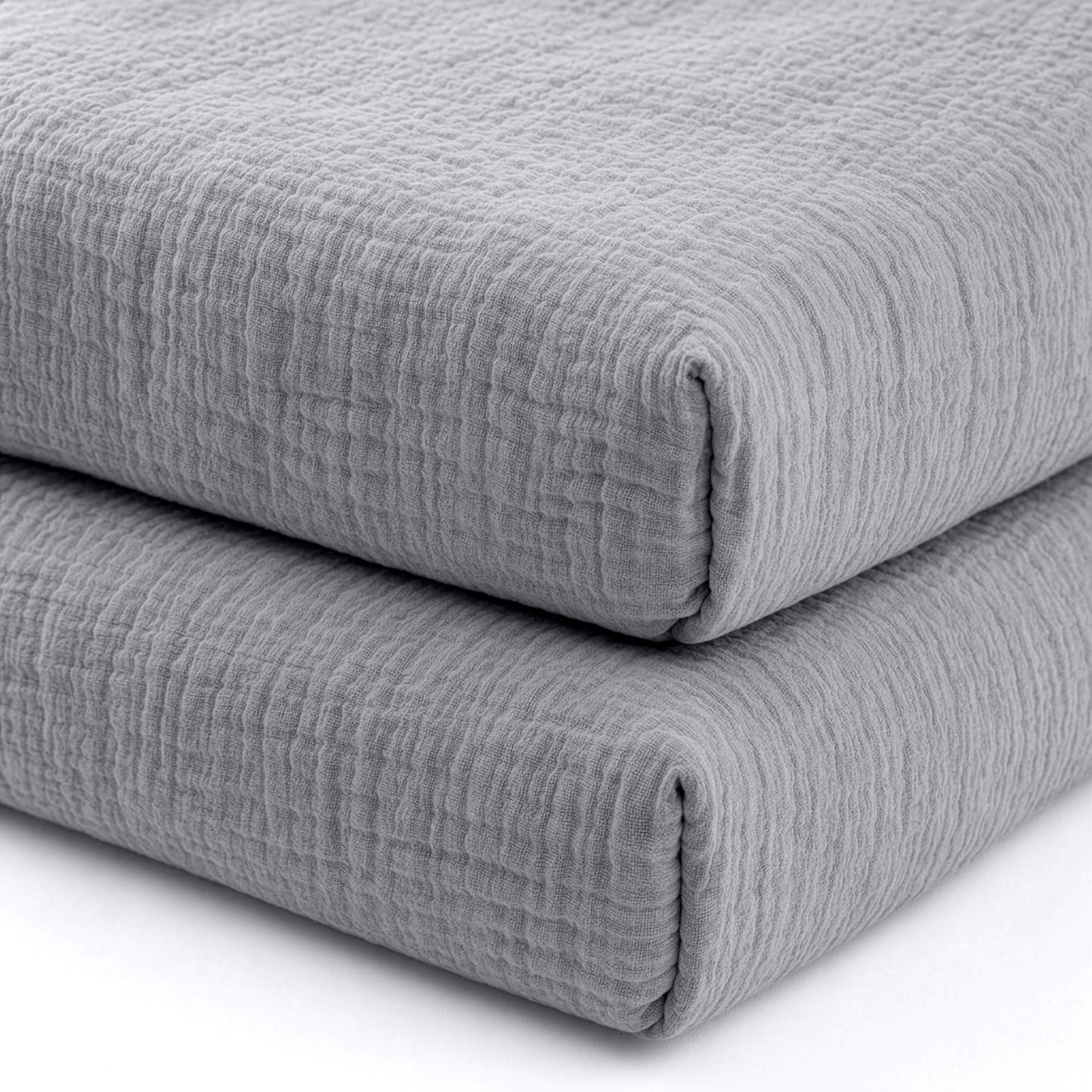 Two neatly folded, textured gray Newton Baby Breathable, Organic Cotton Sheets (2-pack) stacked together against a white background, highlighting their soft, cozy quality for your crib.