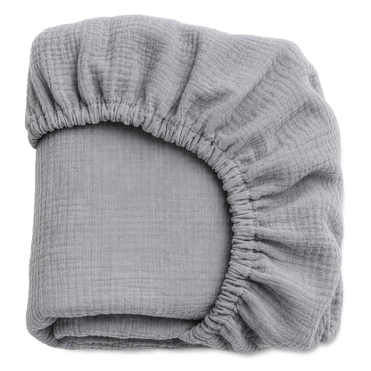 A pair of light gray, breathable Newton Baby Organic Cotton Sheets (2-pack) with elastic edges, made from soft textured fabric, is neatly folded and displayed against a plain white background.