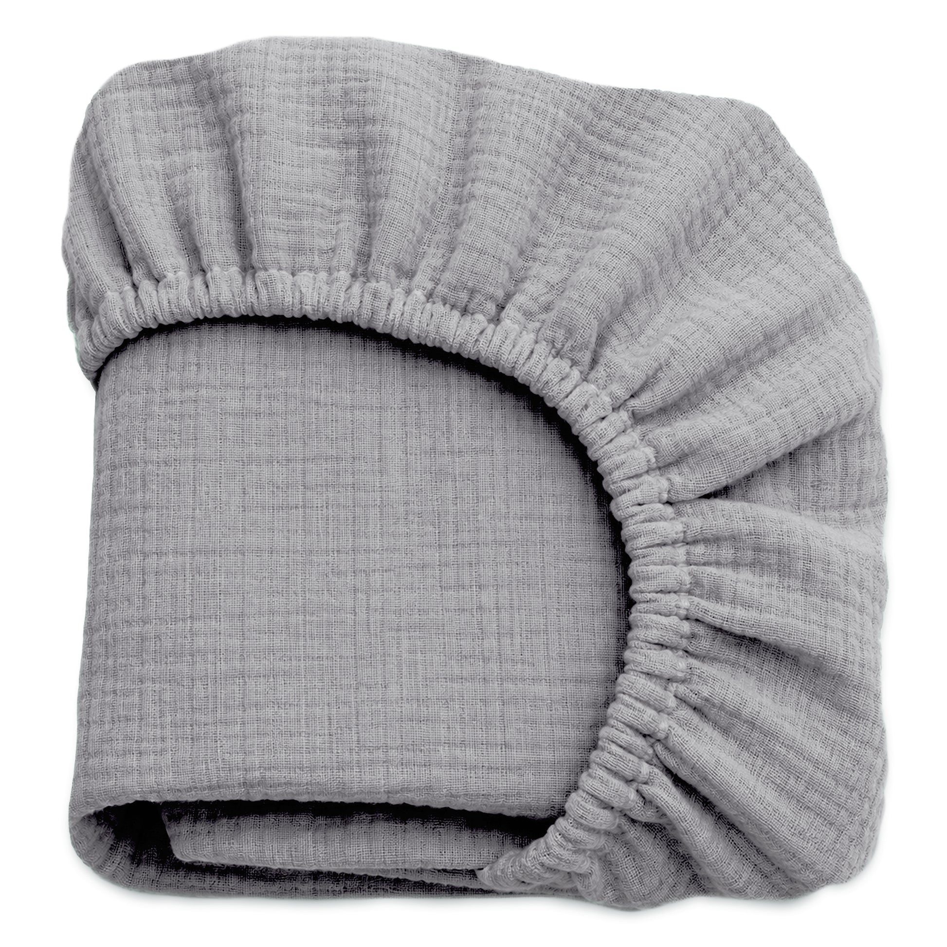A folded, light gray Newton Baby Breathable, Organic Cotton Sheet (2-pack), made from crinkled muslin with elastic edges, is shown against a white background. 999-3020-EVG