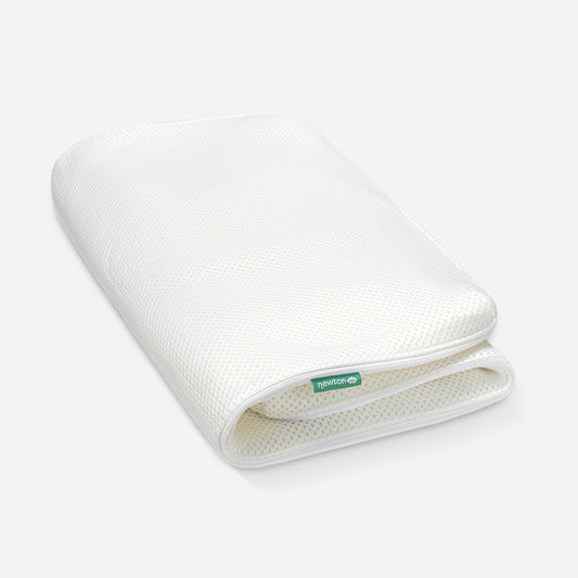 A rolled-up Newton baby mattress cover showing its breathable design, with the Newton logo visible on the edge.