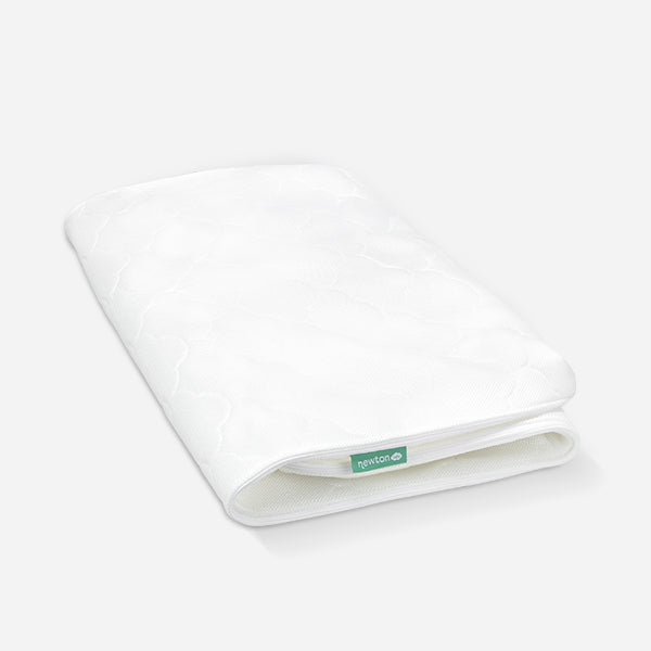 White Newton baby mattress with a breathable, quilted pattern design and a visible brand tag.
