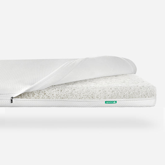 Close-up image of a Newton Baby crib mattress with the cover partially zipped open, revealing its breathable, washable material with a visible logo. skip