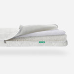 Three-layered Newton baby mattress with top layer partially rolled back to show breathable material, featuring a visible