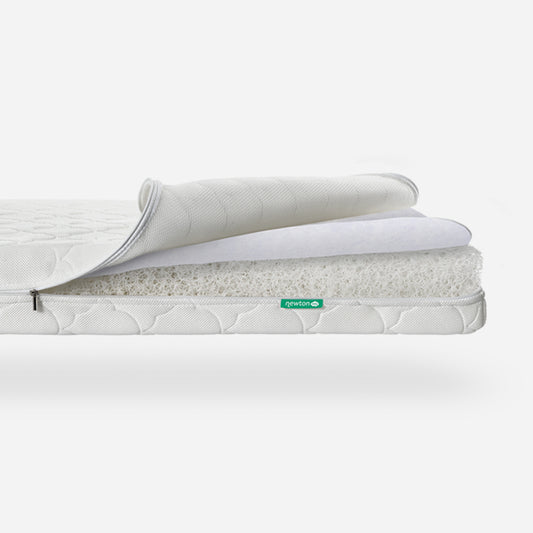 Three-layered Newton baby mattress with top layer partially rolled back to show breathable material, featuring a visible "newton" logo.