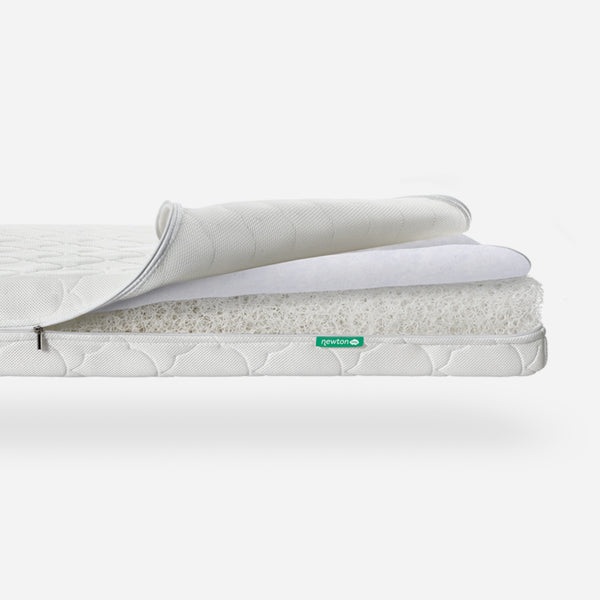 Three-layered Newton baby mattress with top layer partially rolled back to show breathable material, featuring a visible "newton" logo.
