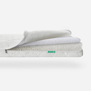 Three-layered Newton baby mattress with top layer partially rolled back to show breathable material, featuring a visible 