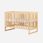 Wooden baby crib with visible mattress on a white background. skip