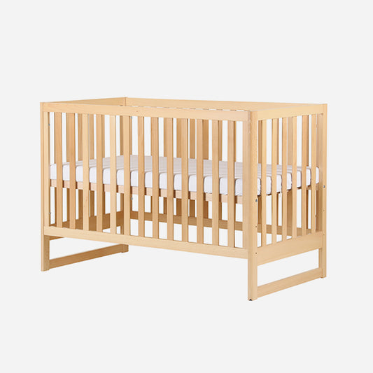 Wooden baby crib with visible mattress on a white background. skip