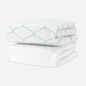 Stack of two soft crib sheets, two featuring a light blue scalloped cloud pattern and one in solid white. skip