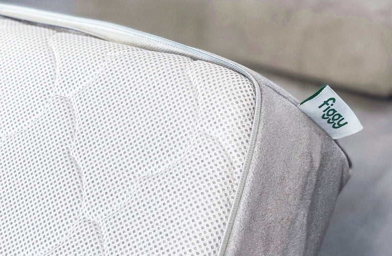 Close-up of a breathable baby mattress with a textured fabric and a visible 'figgy' label on the side.