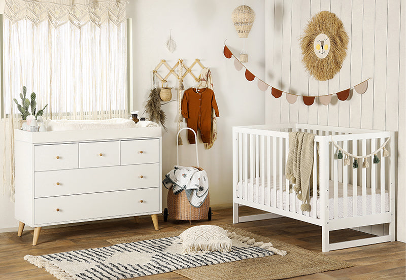 A cozy and stylish nursery room featuring a white crib and dresser, decorated with warm, earthy tones, and playful safari accents. 500-8200-WHT