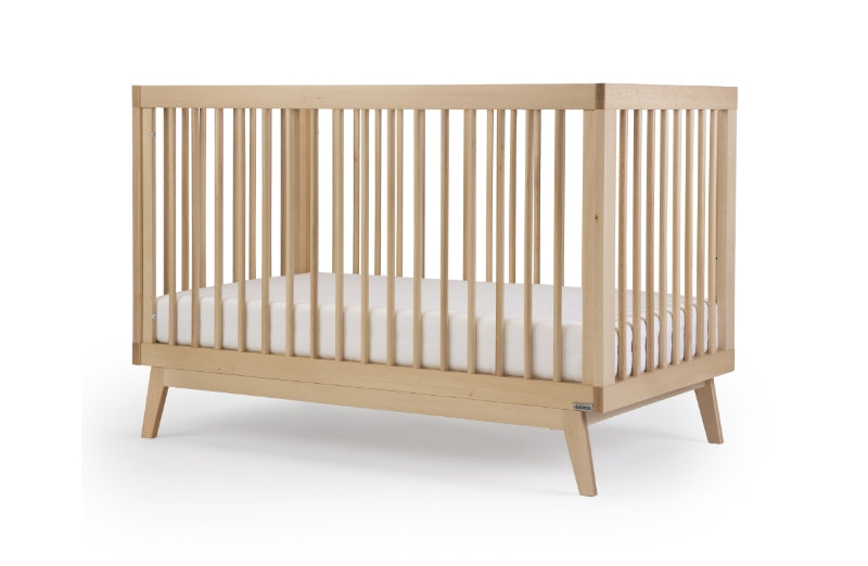 Modern wooden baby crib with a white mattress, set against a clean white background. Soho Convertible Crib