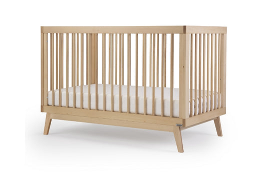 Modern wooden baby crib with a white mattress, set against a clean white background. Soho Convertible Crib